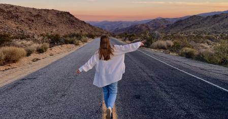 Le processus de placement Une fille au pair court dans le désert, les bras grands ouverts, le long de l'autoroute.